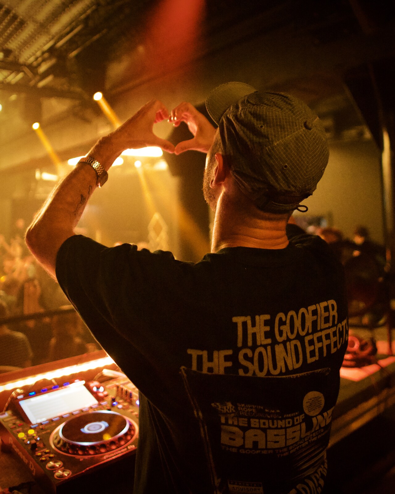 DJ making heart hands at the decks, warm light